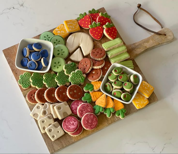 a wooden cutting board topped with lots of different types of cookies