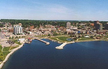 an aerial view of a city with water and trees in the foreground, surrounded by tall buildings