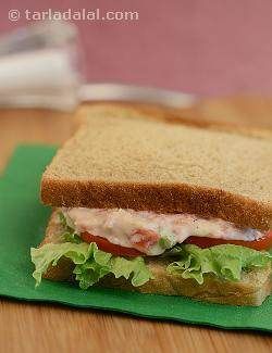 a sandwich with lettuce, tomato and mayonnaise sitting on a green napkin