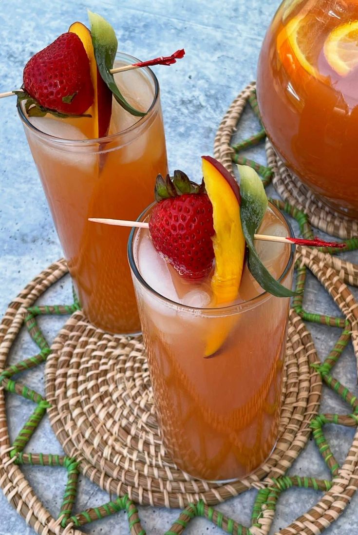 two glasses filled with drinks sitting on top of a wicker tray next to each other