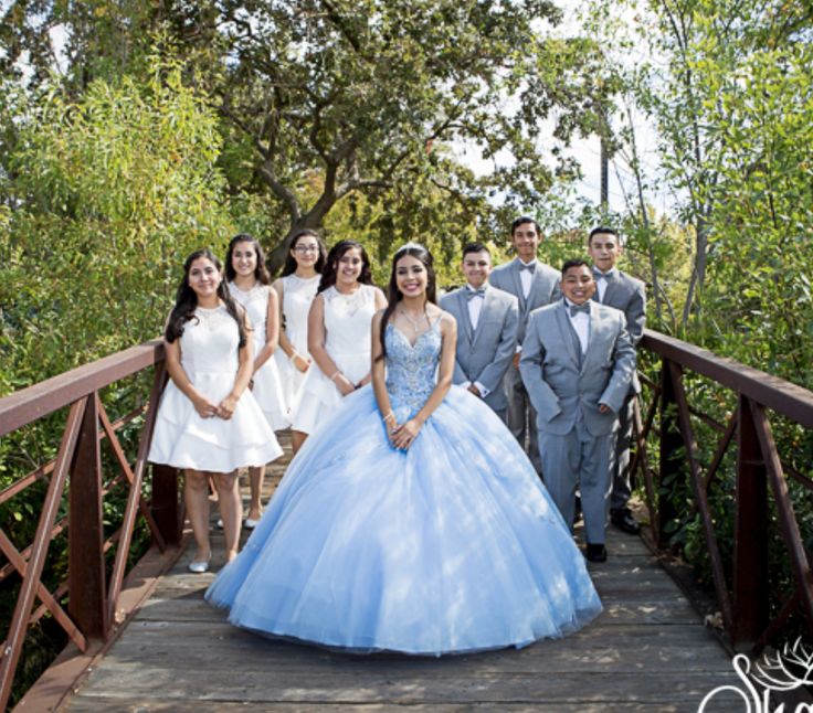 a group of people standing on top of a wooden bridge next to eachother