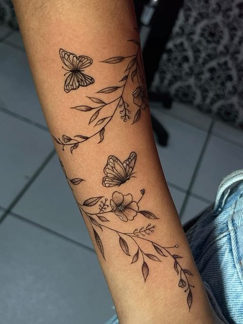 a woman's arm with butterflies and flowers tattooed on the side of her arm