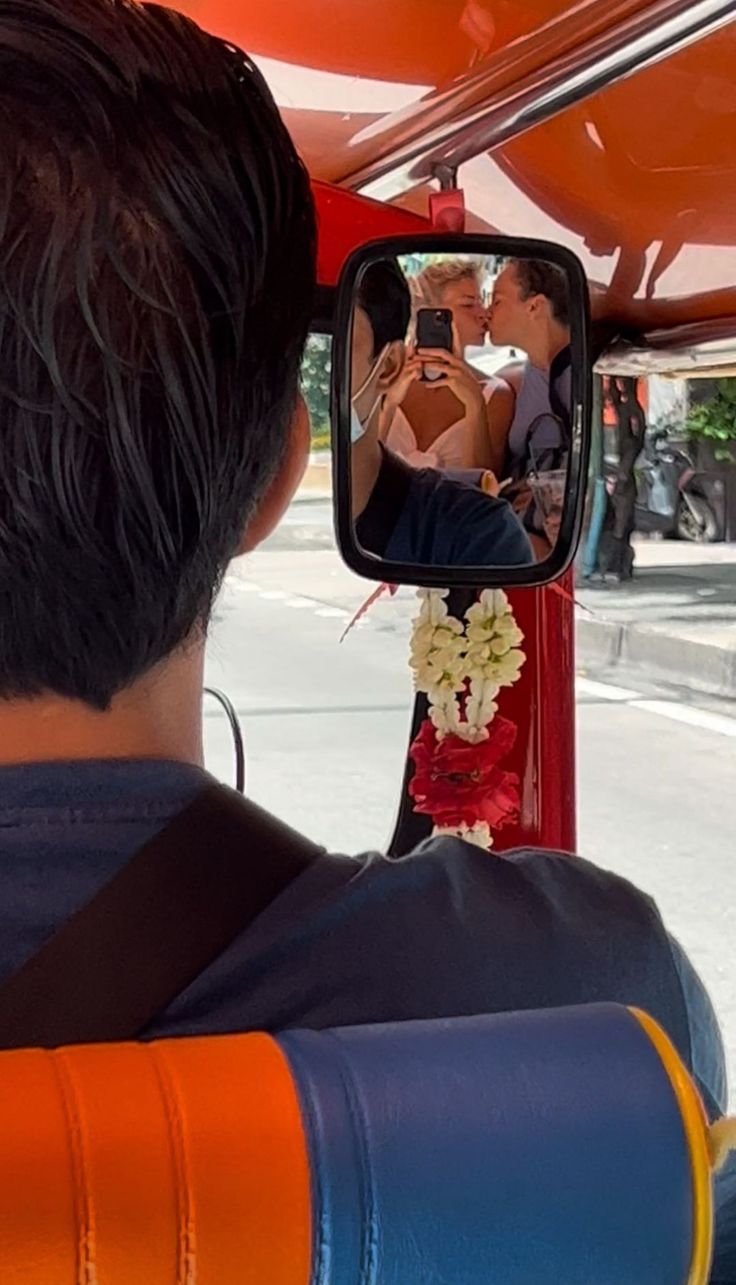 a man taking a picture of himself in the rear view mirror of a bus with his cell phone