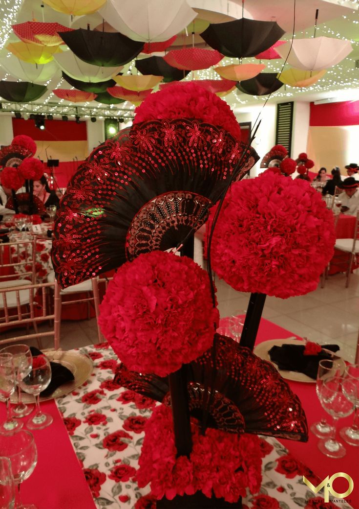 red flowers and umbrellas are on the table at a wedding reception in a banquet hall