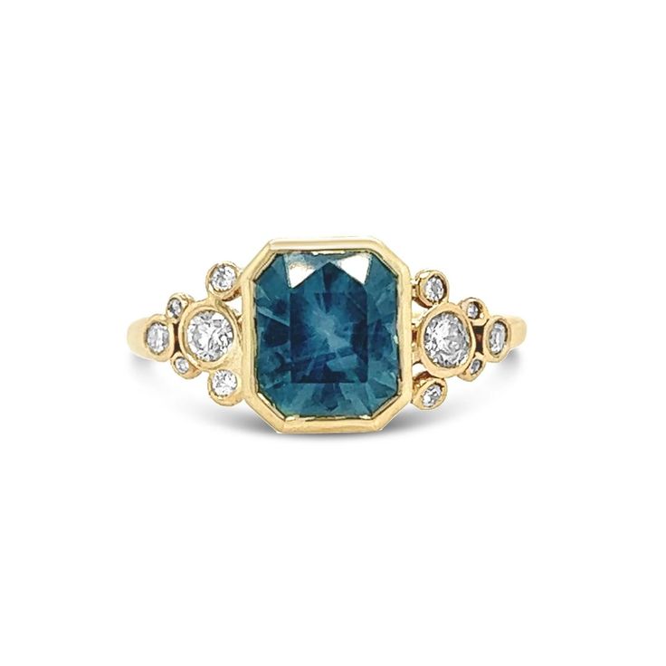 Emily fell in love with this Montana Sapphire in Tucson when she met the husband and wife who pulled it from the ground in their mine and carved it in this amazing modified radiant cut. The dramatic faceting of the stone enhanced its unique blue and teal coloring while preserving the sparkle. Set with 1/4 ct brilliant white diamond and Emily's signature seagrass band in 14k gold Approx stone size: 9mm x 8mm Approx sapphire weight: 3ct Approx diamond weight: .25ct Stone in setting stands about 5. Blue Emerald Cut Ring With Bezel Setting, Blue Emerald Cut Rings With Bezel Setting, Blue Emerald Ring With Bezel Setting, Blue Octagon Diamond Ring, Fine Jewelry Blue Radiant Cut Sapphire Ring, Blue Radiant Cut Ring With Prong Setting, Blue Emerald Cut Cluster Ring With Center Stone, Blue Rings With Rectangular Accent Stones, Blue Diamond Emerald-cut Cluster Ring