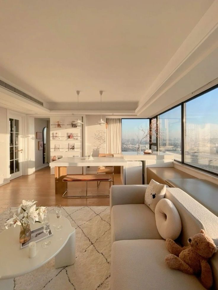 a living room filled with furniture and a large window overlooking the cityscape in the distance