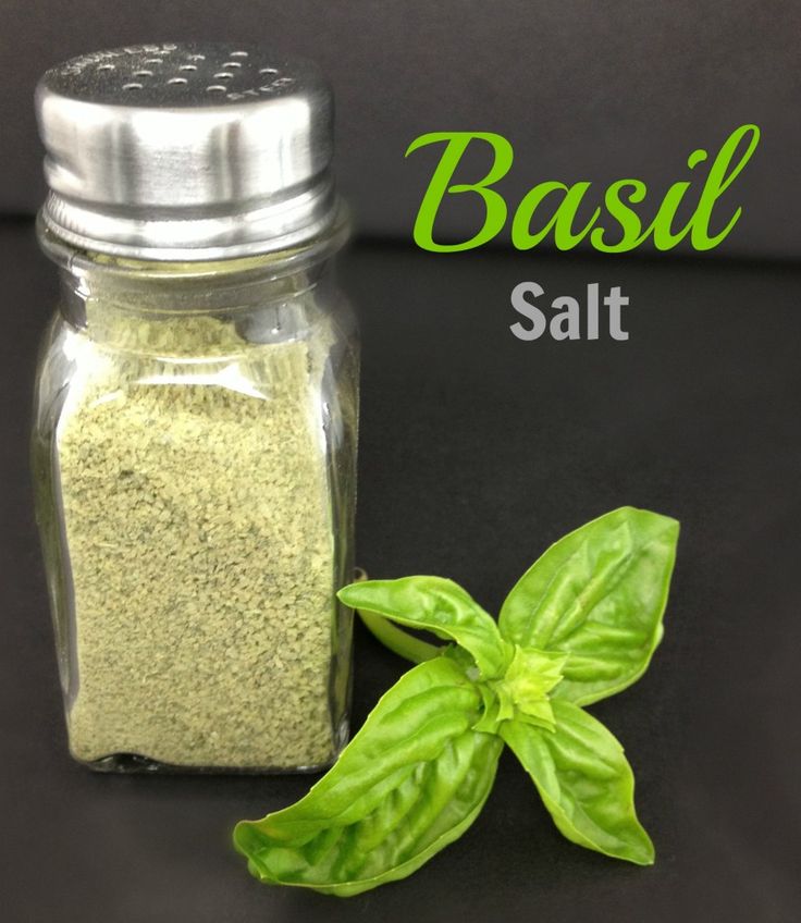 basil salt in a glass jar next to a fresh basil plant with the words basil salt above it