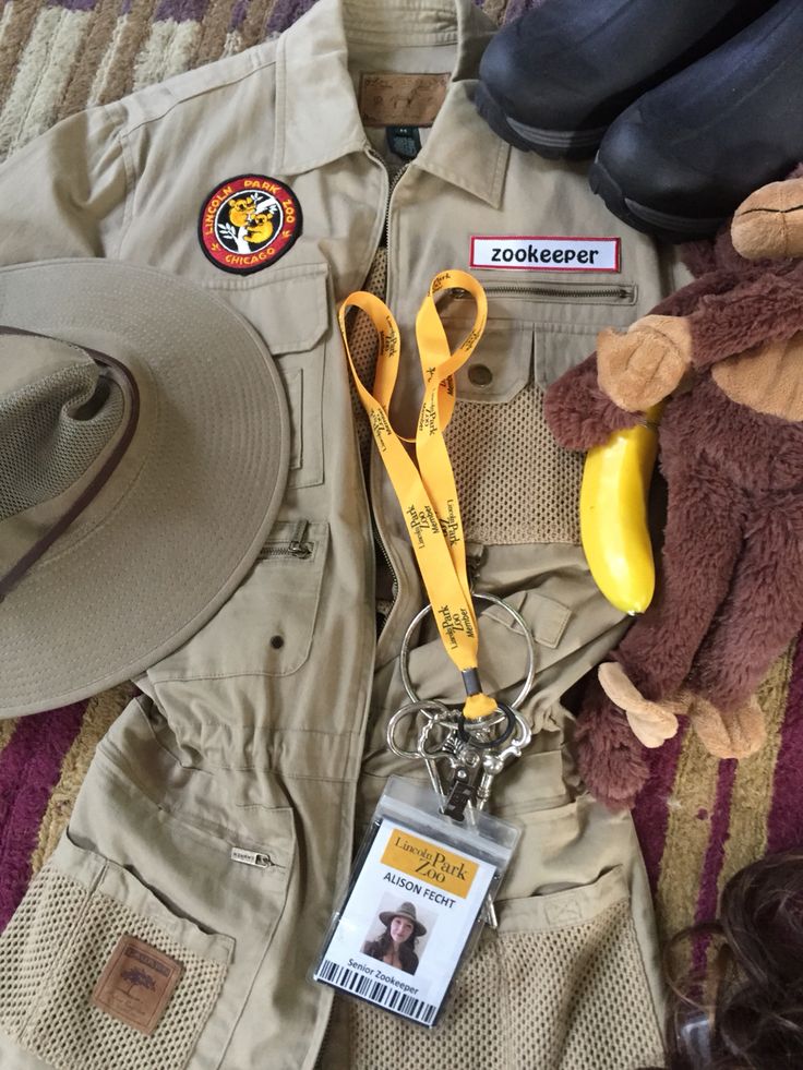 a hat, badge and other items are laid out on a bed with the name zookeeper attached to it