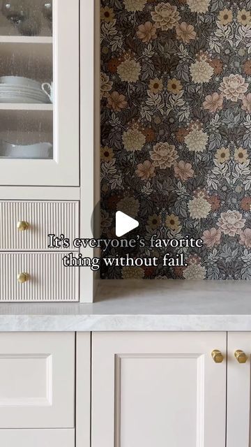 a kitchen with white cabinets and floral wallpaper on the backsplash is featured in this video