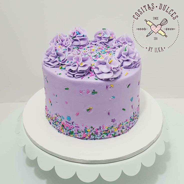 a purple cake with sprinkles and frosting on a white platter