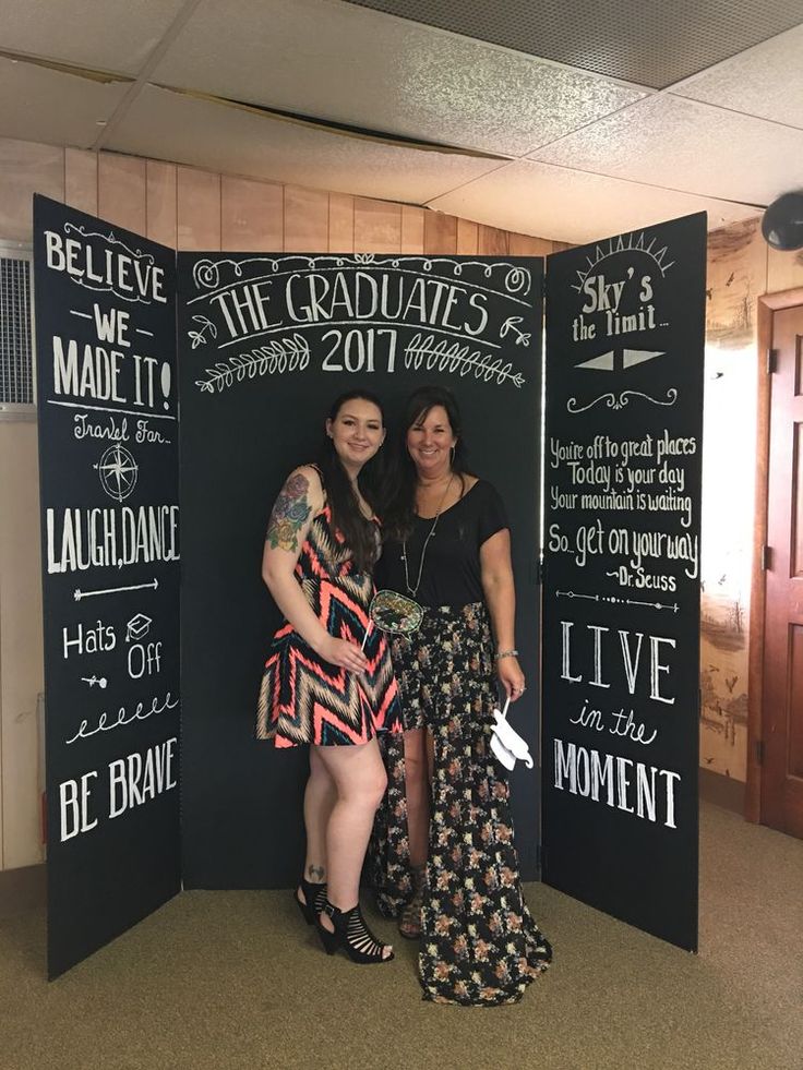 two women standing next to each other in front of a chalkboard wall with writing on it