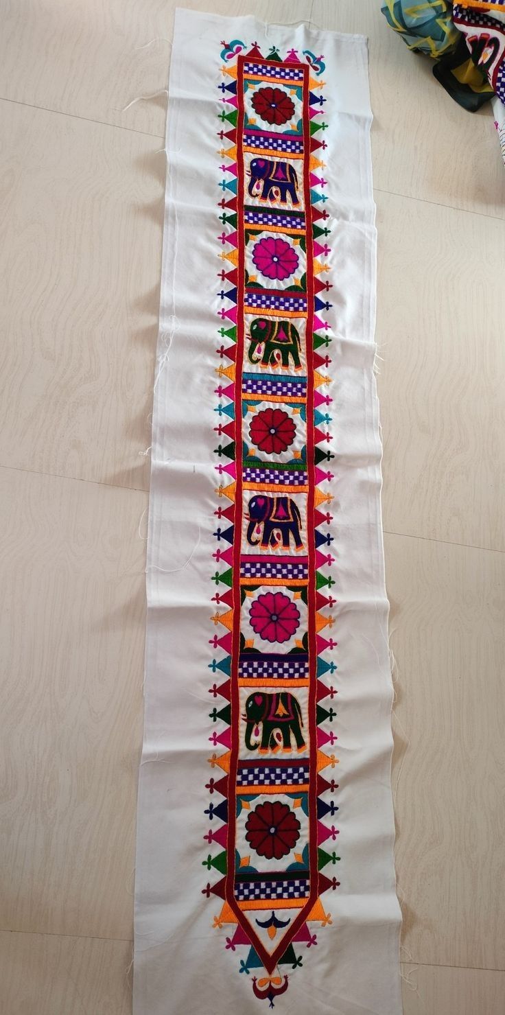 a white table runner with an elephant design on the side and other decorations around it