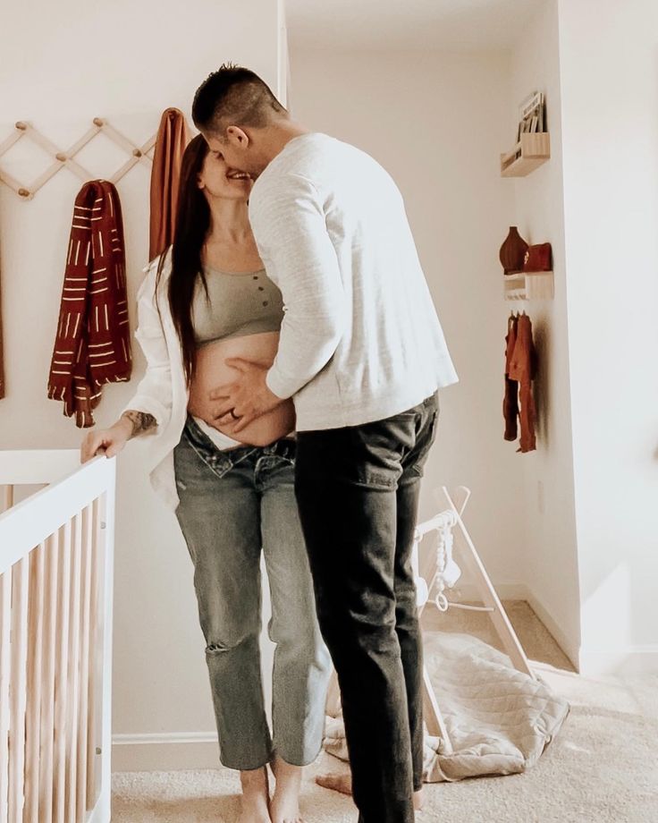 a man and woman standing next to each other in front of a baby crib