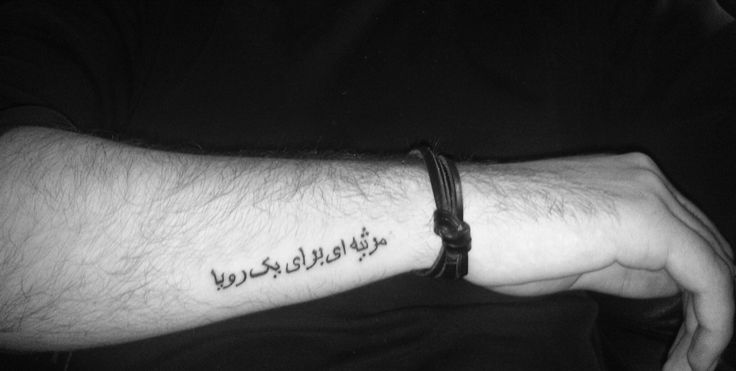 a man with a wrist tattoo that says, we are all in this world