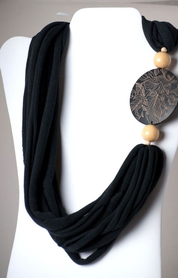 a black necklace with wooden beads and tassels on a white mannequin