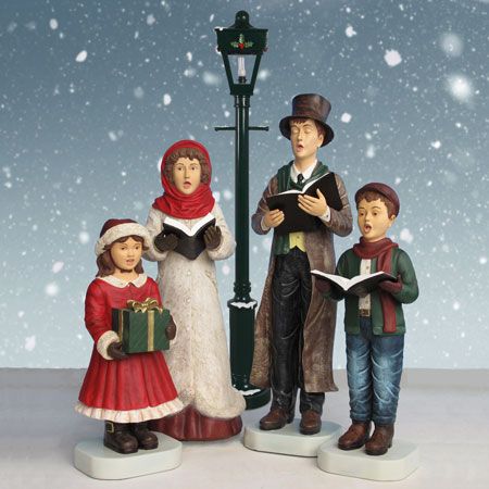 three figurines are standing in front of a street light and lamp post, with snow falling on the ground behind them