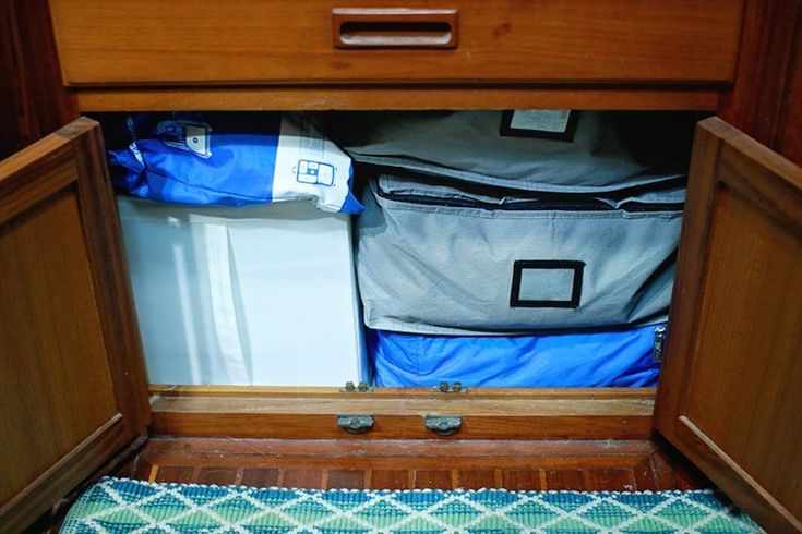 an open suitcase sitting on top of a wooden floor next to a blue and white rug