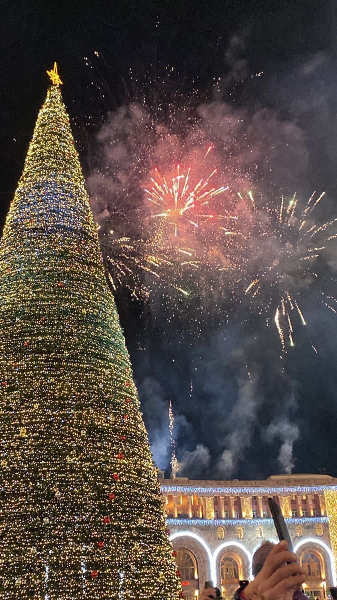 a large christmas tree with fireworks in the background