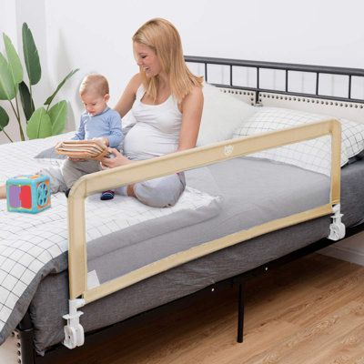 a woman sitting on top of a bed next to a baby in a crib