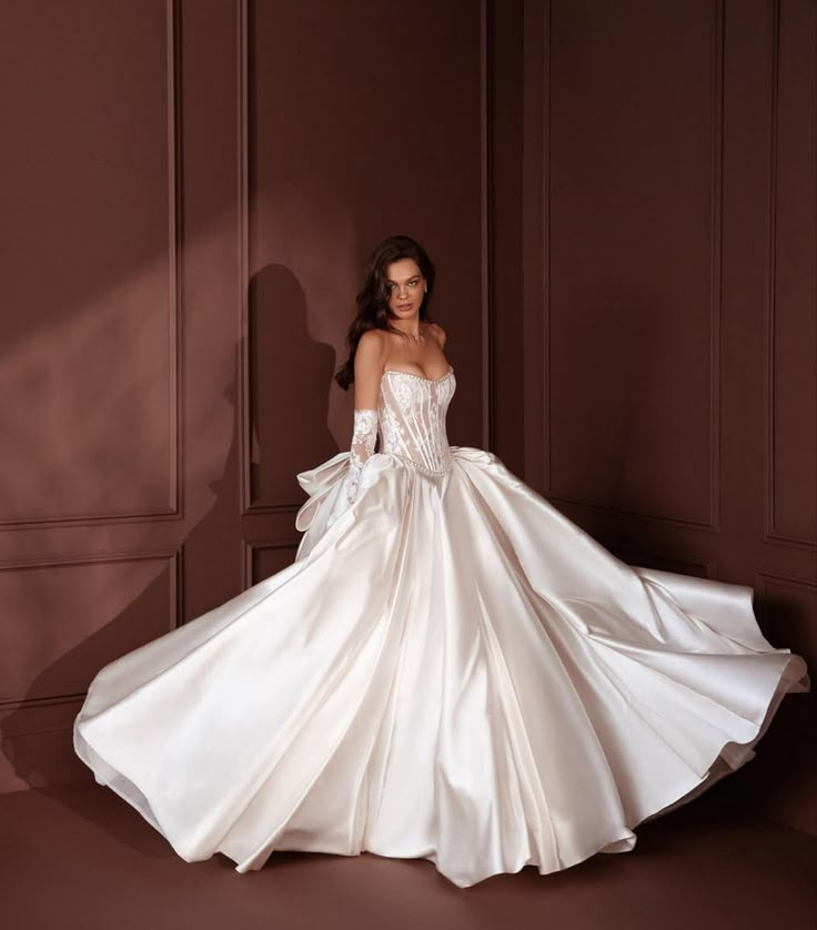 a woman in a white wedding dress posing for the camera with her hands on her hips