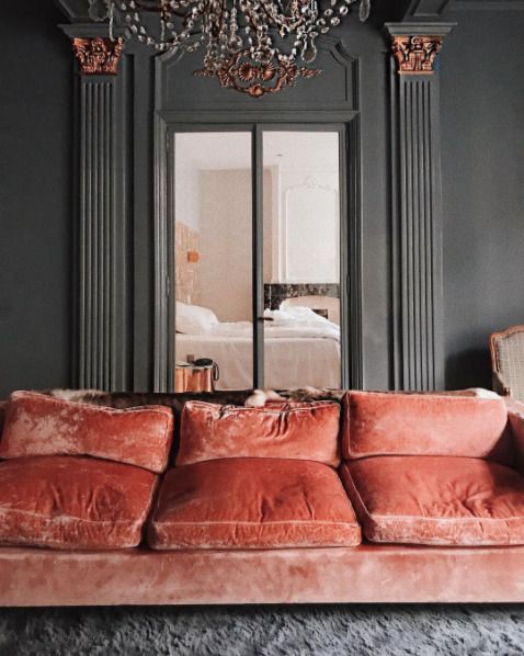 a living room with a couch, chandelier and mirror