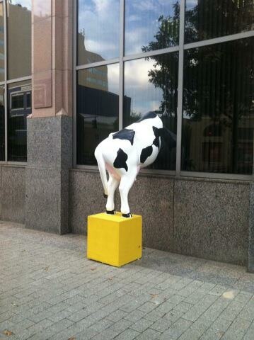 a cow statue sitting on top of a yellow box