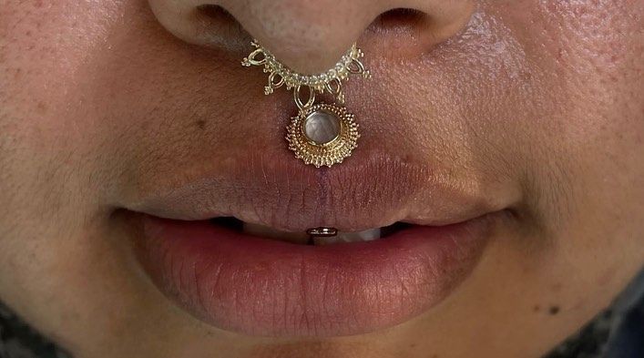 a close up of a person with a nose ring attached to their nose and wearing a necklace