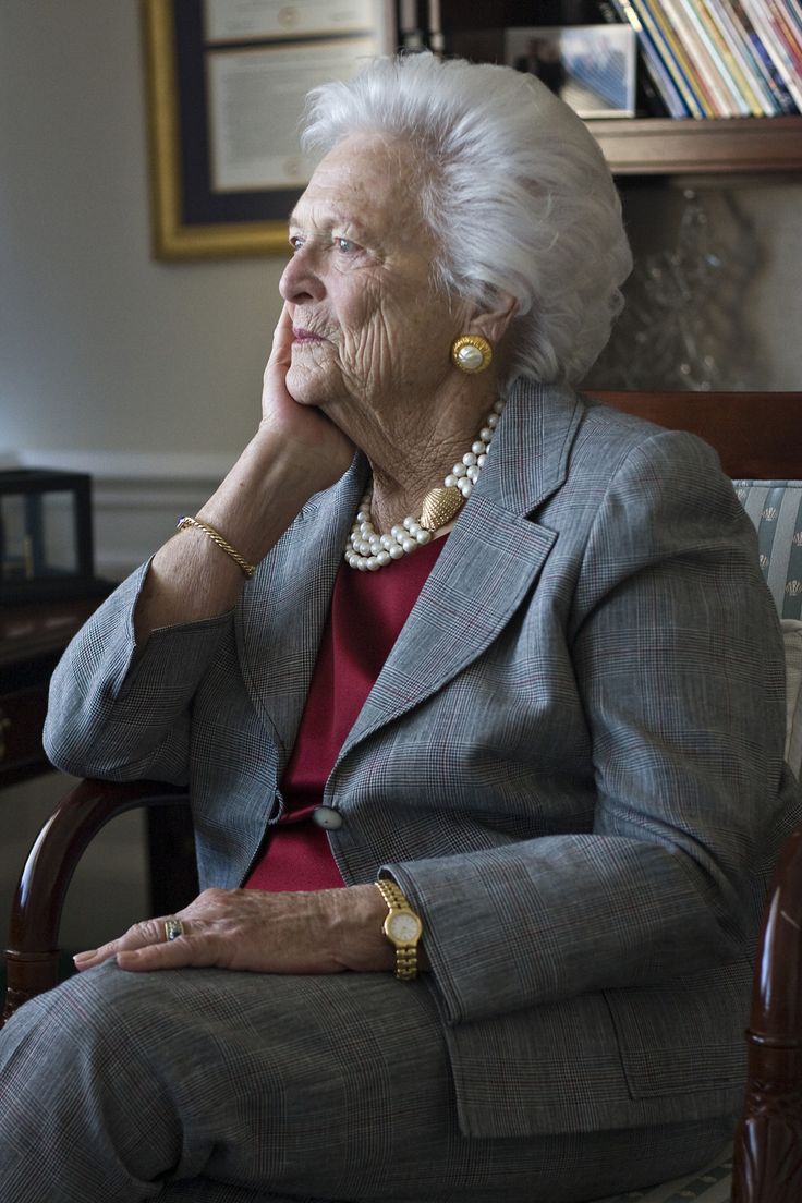 an older woman sitting in a chair with her hand on her chin and looking off to the side