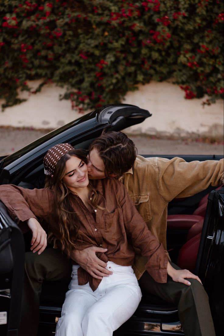 a man and woman sitting in the back of a black car with their arms around each other