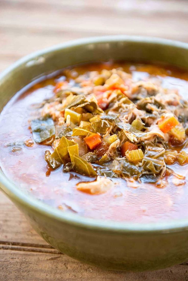 a green bowl filled with soup on top of a wooden table