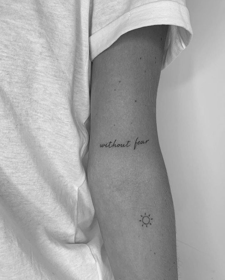 a person with a small tattoo on their arm that says, without fear in black and white