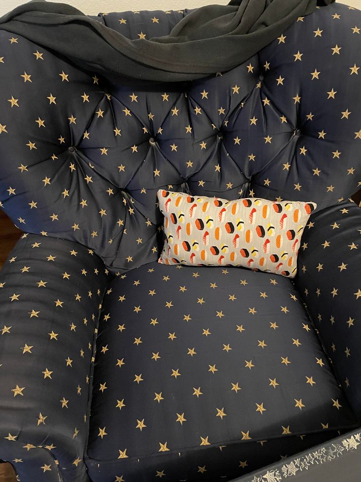 a black chair with gold stars on it and a pillow in the back cushion that is folded over