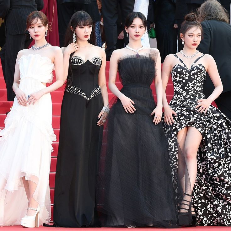 four women in black and white gowns standing on the red carpet at an event