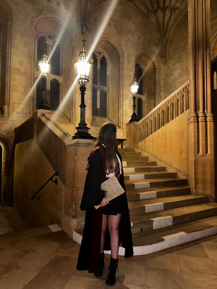 a woman standing in front of a set of stairs with light shining down on her