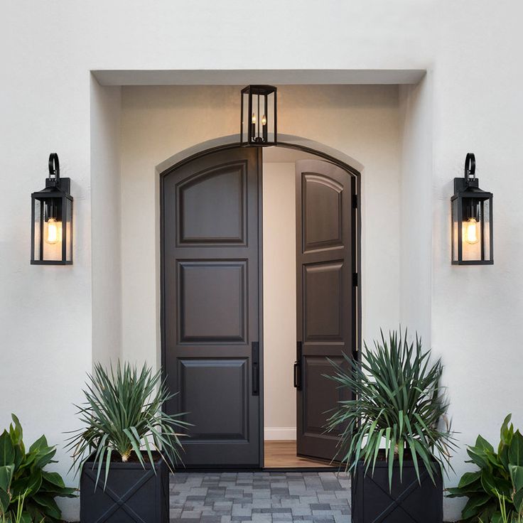 two planters with plants are in front of the entrance to a house that is painted white