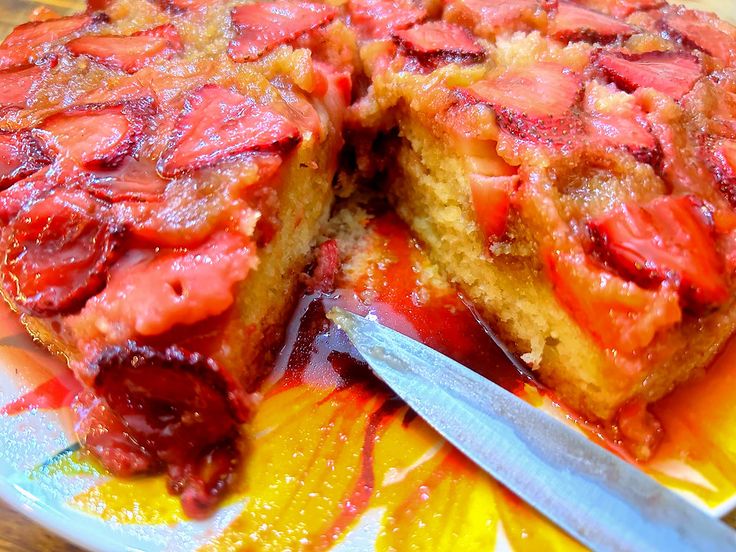 a strawberry upside down cake on a plate with a knife