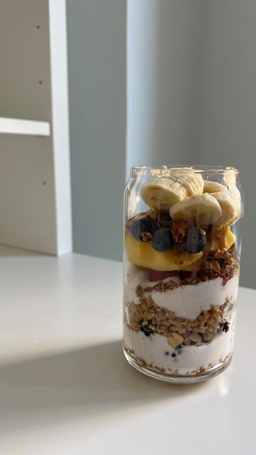 a glass jar filled with food sitting on top of a white table next to a window