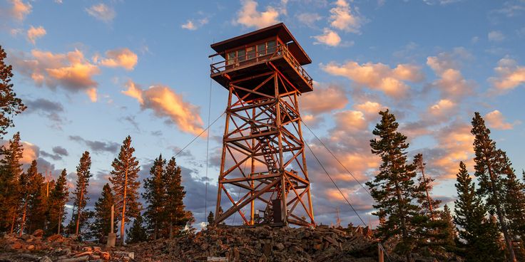 a tall tower sitting on top of a rocky hillside under a blue sky with clouds