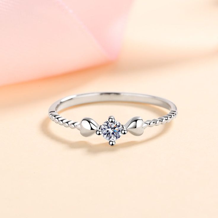 a white gold ring with an angel wing design on the side and a diamond center