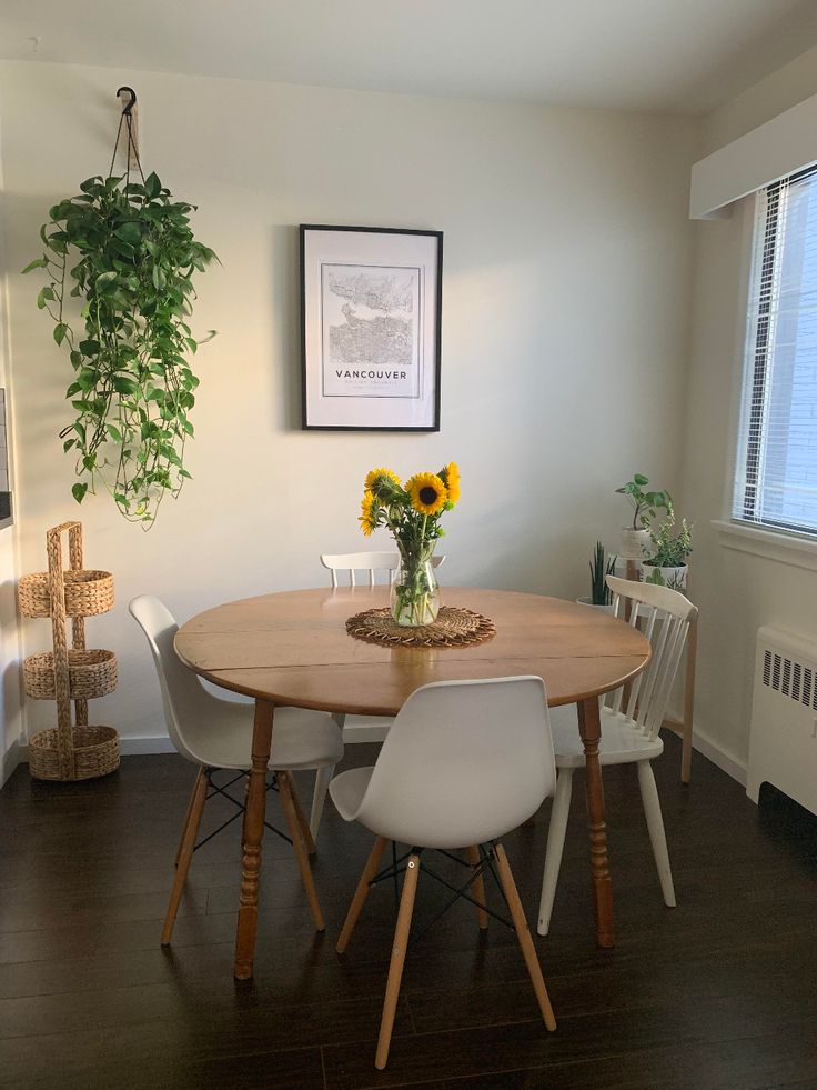 a dining room table with white chairs and sunflowers