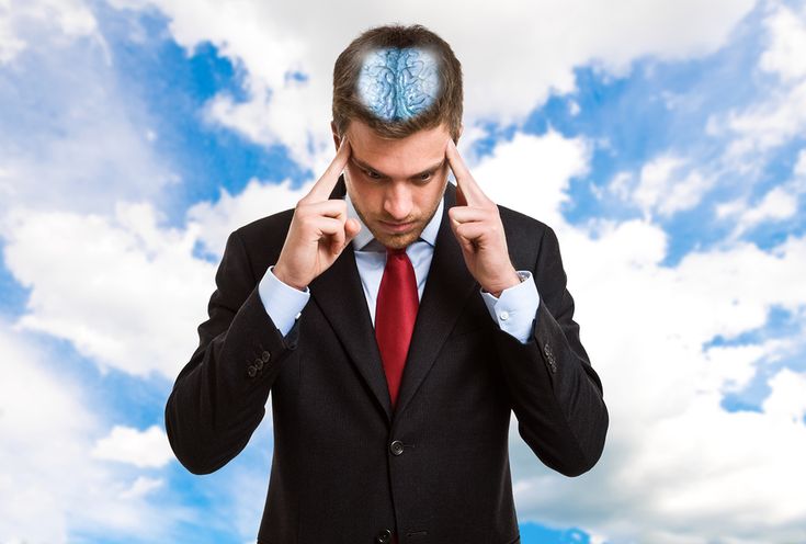 a man in a suit holds his head with both hands and points at the brain