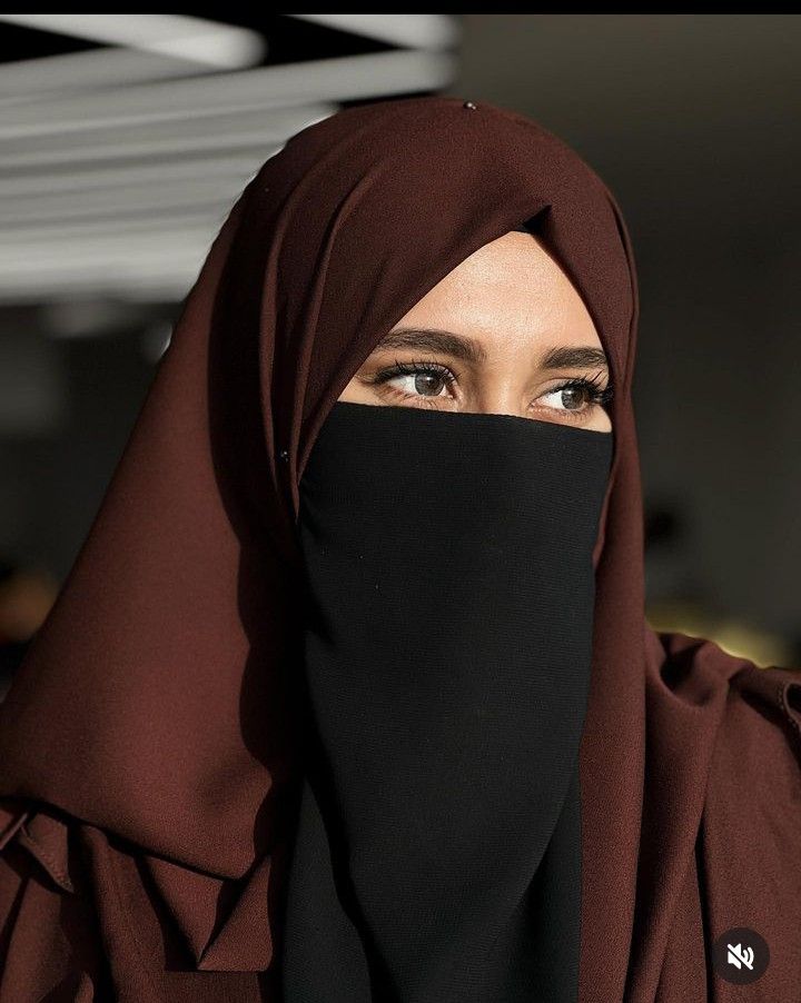 a woman wearing a black hijab and looking off to the side with her eyes wide open