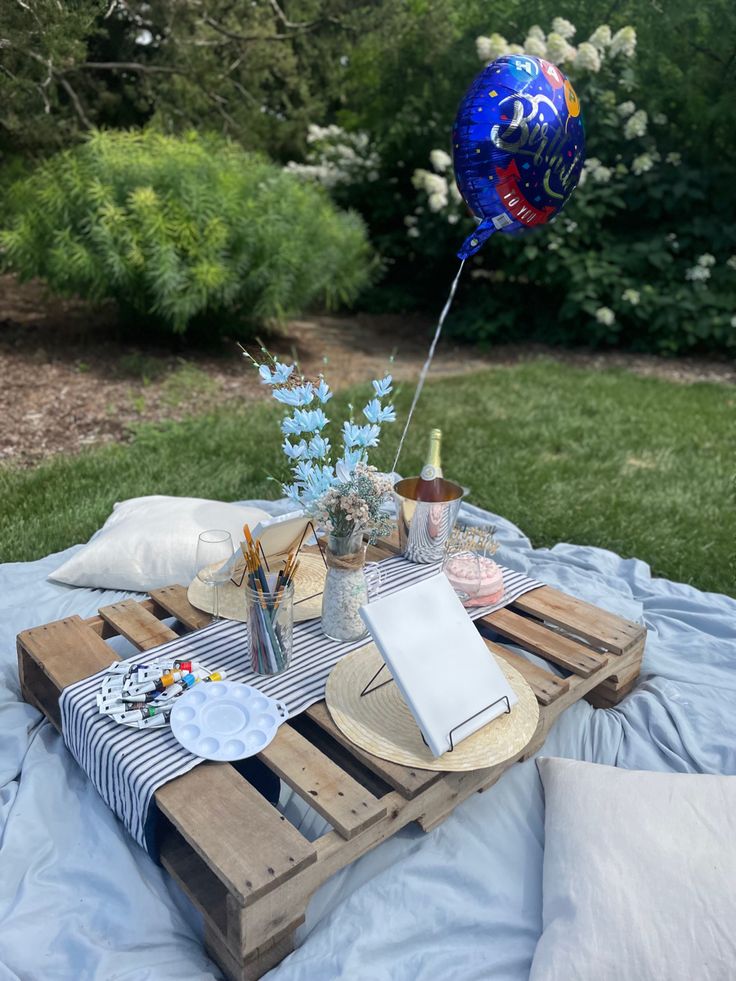 a picnic table set up with balloons and plates