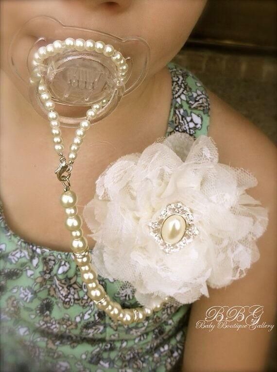 a close up of a person wearing a necklace with flowers on it and pearls around the neck