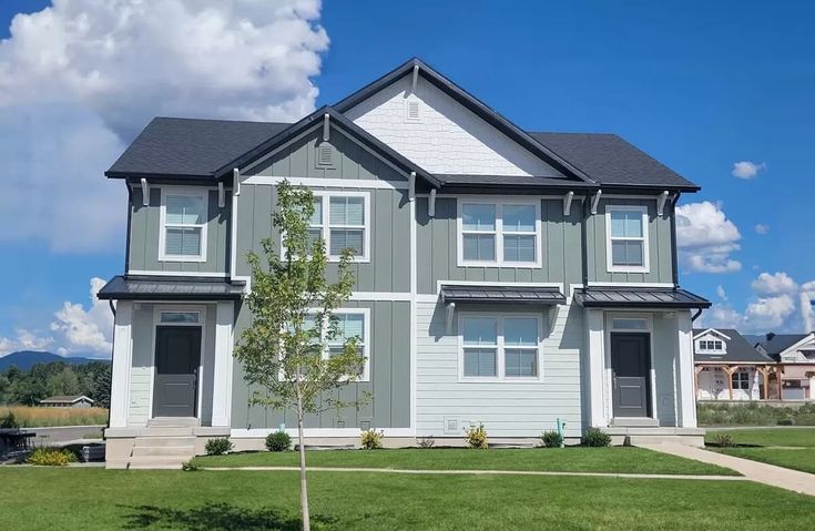 the front of a two story house with green grass and blue sky in the background