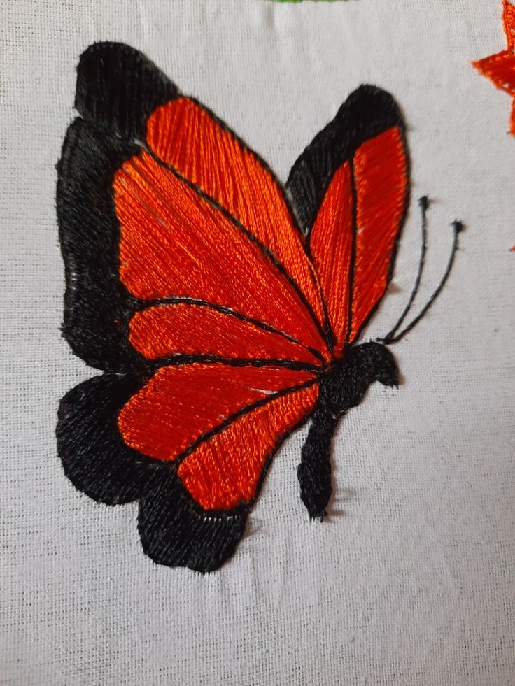 an orange and black butterfly sitting on top of a white cloth