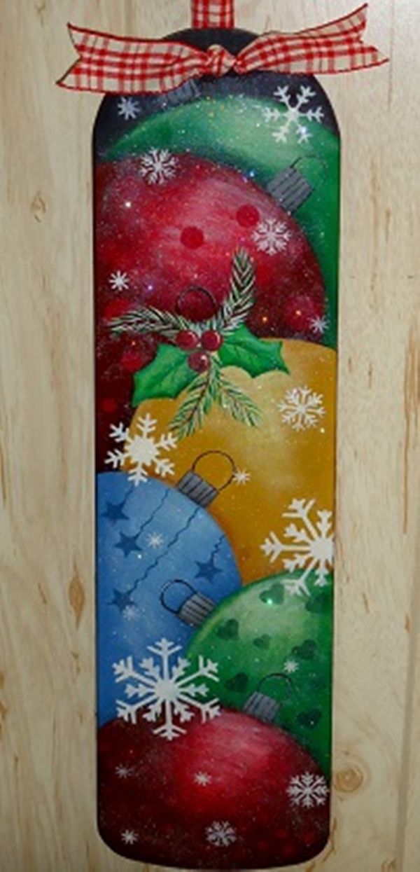 a wooden door hanger decorated with christmas ornaments and snowflakes on it's side