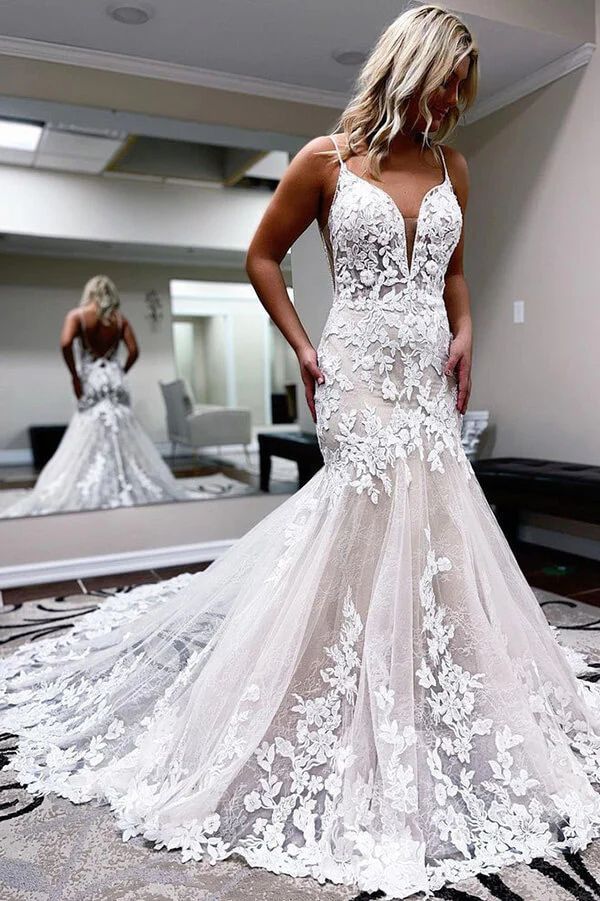 a woman standing in front of a mirror wearing a wedding dress with an open back