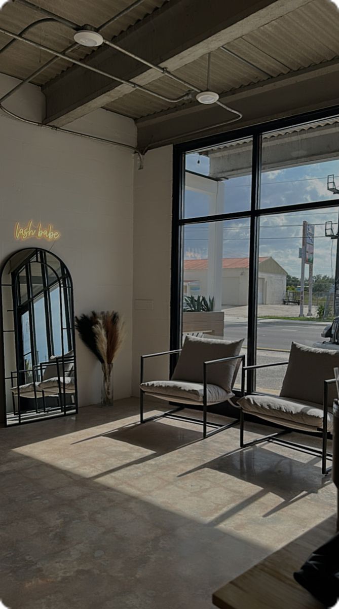 an empty room with chairs and mirrors in the corner, looking out onto the street