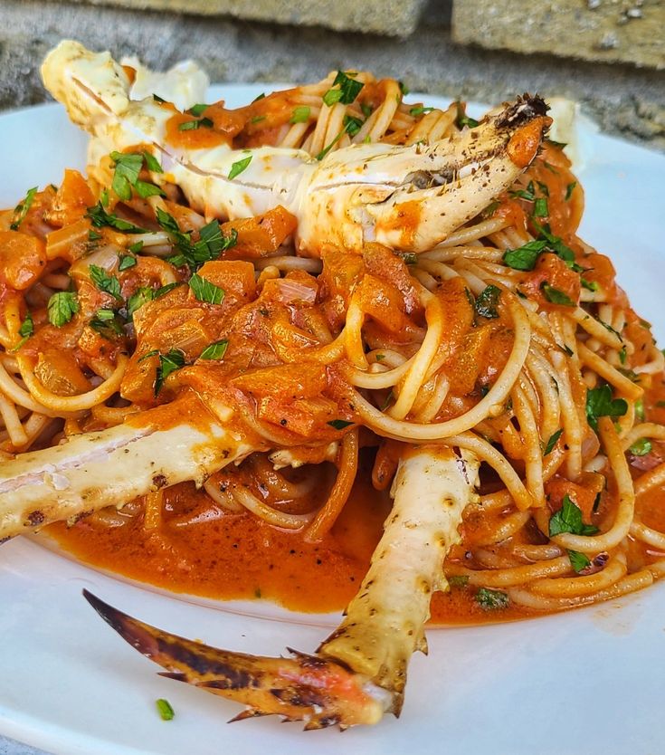 a white plate topped with pasta covered in sauce and shrimp on top of it next to a fork